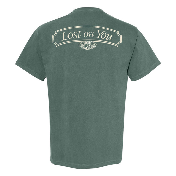 A green Tigers Jaw Comfort Colors short-sleeve tee shown from the back, featuring "Lost on You" in a decorative cream font within a curved border near the upper backโan exclusive design not found elsewhere.