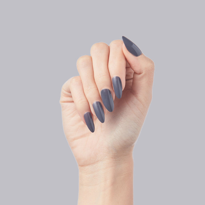 100% Chance - Press-On | Long | Almond showing hand with long almond false nails in moody gunmetal blue polish on gray background