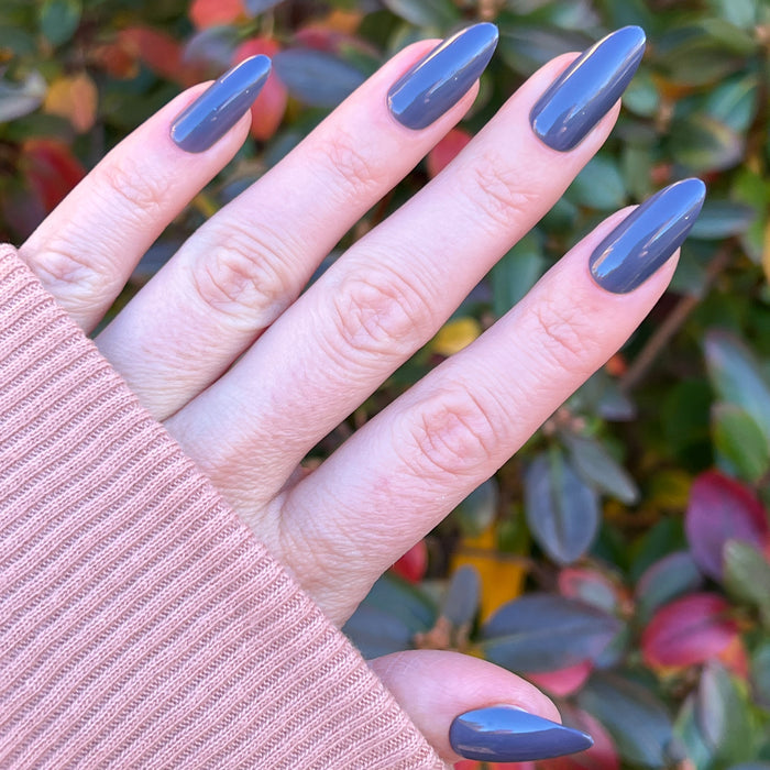 100% Chance - Press-On | Long | Almond showing hand with long almond-shaped glossy gunmetal blue nails outdoors