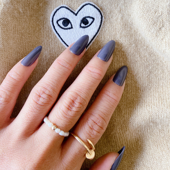 100% Chance - Press-On | Long | Almond showing hand with long almond nails in moody gunmetal blue polish indoors