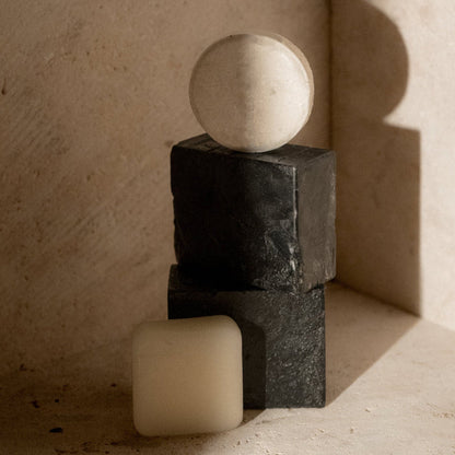 Charcoal bar soap with a pale bar on the side; stacked black rectangular soaps
