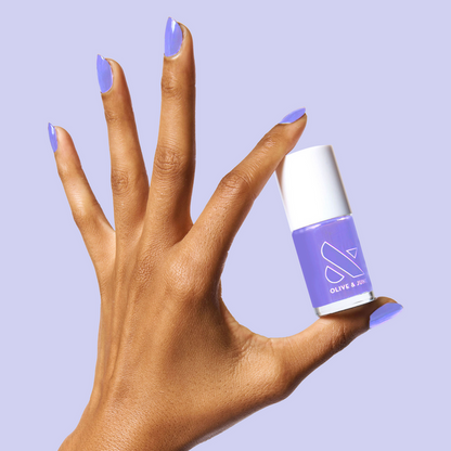 Hand with nails painted in Bold & Unshaken purple gel polish holding Olive and June polish bottle for a vibrant manicure
