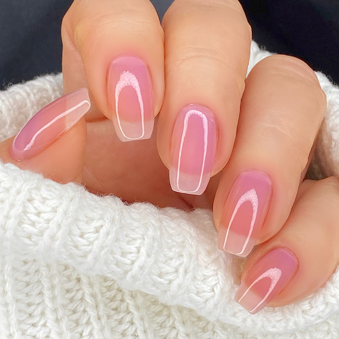 Bold sheer pink lavender nail polish close-up on a light skin tone with a white sweater