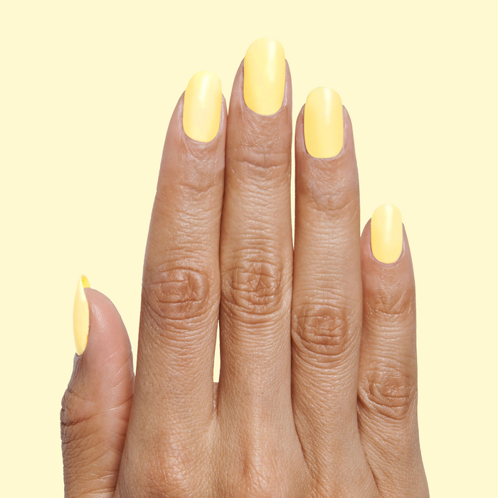 Hand with nails painted in Bright & Focused yellow for a bright, creative at-home manicure look using gel polish