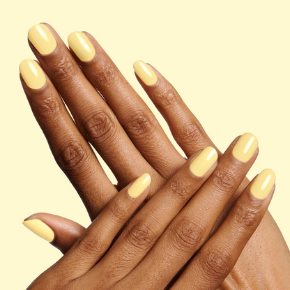 Hands with nails painted in Bright & Focused yellow gel polish for a vibrant and creative at-home manicure look