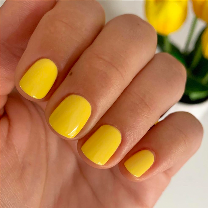 Hand displaying Bright & Focused yellow gel polish nails for a bright and cheerful at-home manicure look