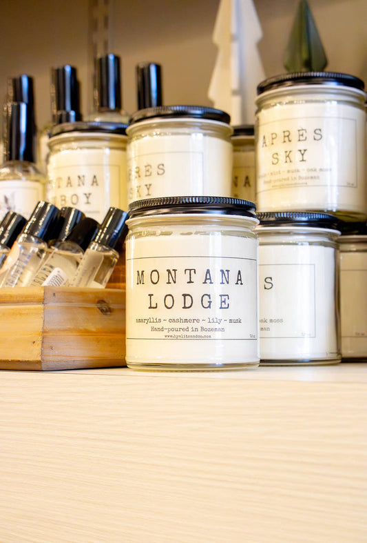 Hyalite & Co Montana Lodge candle in a rustic jar with a wooden lid, showcasing a cozy cabin scene on the label.