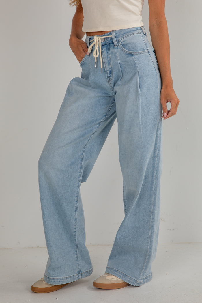Light blue jeans worn by a person on a plain background