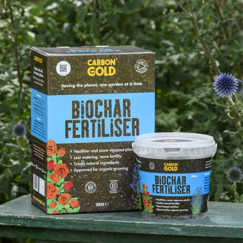 Packaging and container of Carbon Gold Biochar Fertiliser placed against a gardening backdrop.