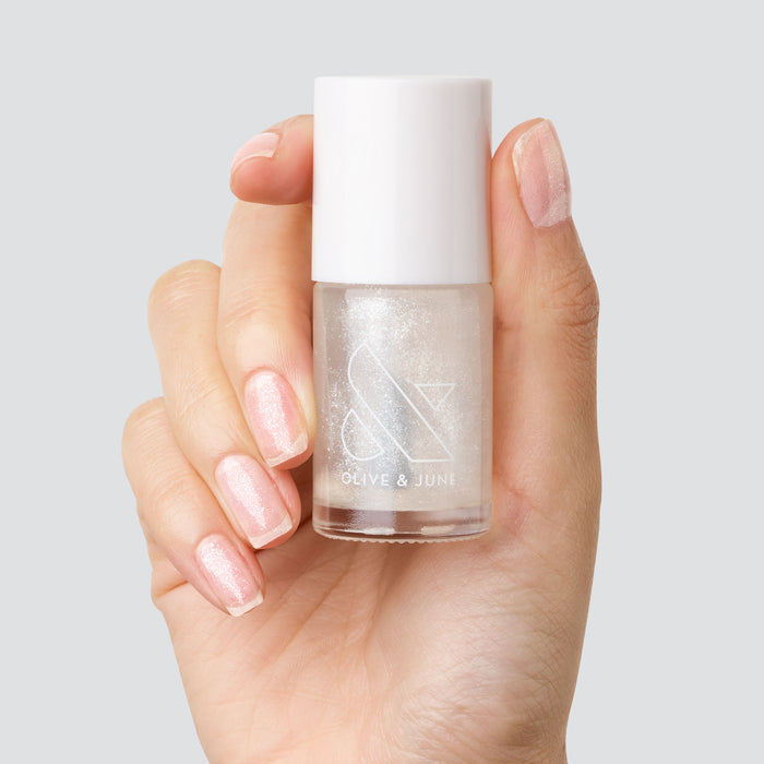 Hand holding a bottle of COSMIC clear shimmer polish with nails coated in a subtle sparkling finish