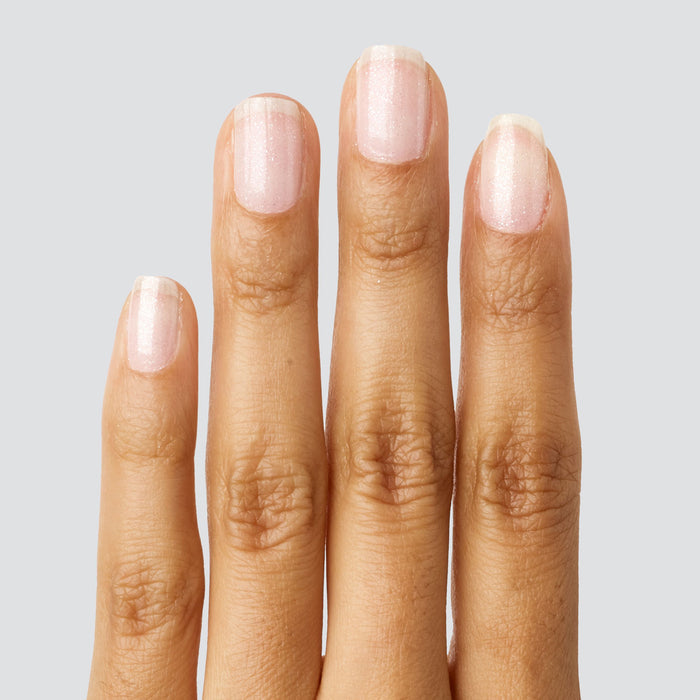 Fingers with natural nails coated in COSMIC clear polish adding a soft shimmer for subtle manicure shine