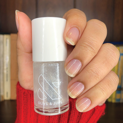 Hand holding a bottle of COSMIC shimmer polish with nails coated in a sheer sparkling finish for a natural mani look