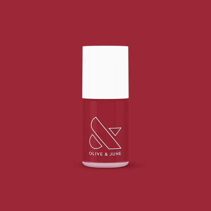 Bottle of Olive and June Cozy Up nail polish in warm brick red for mani and at-home manicure looks