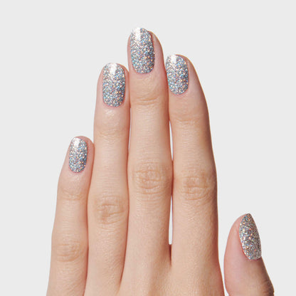 Hand with nails painted in Exclamation Point silver holographic glitter polish for a sparkling at-home manicure