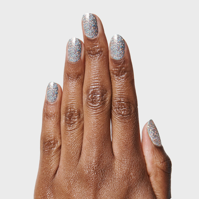 Hand with nails painted in Exclamation Point silver holographic glitter polish for a dazzling at-home manicure