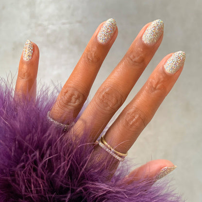 Hand with nails painted in Exclamation Point silver holographic glitter polish for a shimmering at-home manicure