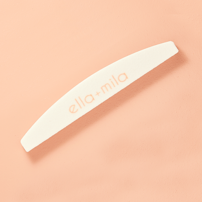 White half-moon nail file and buffer on a peach background
