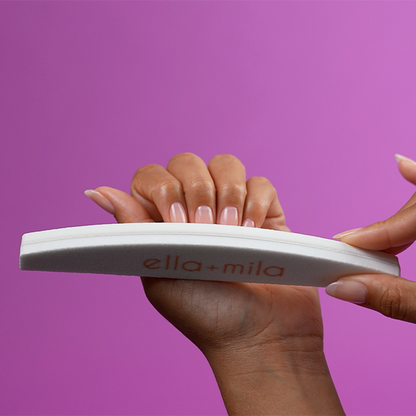 Buffing nails with the white half-moon file buffer on a purple background