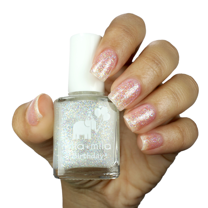 First Birthday iridescent glitter nail polish manicure on a light skin tone with the bottle