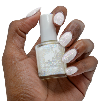 First Birthday iridescent micro glitter nail polish on a deep skin tone, hand holding the bottle