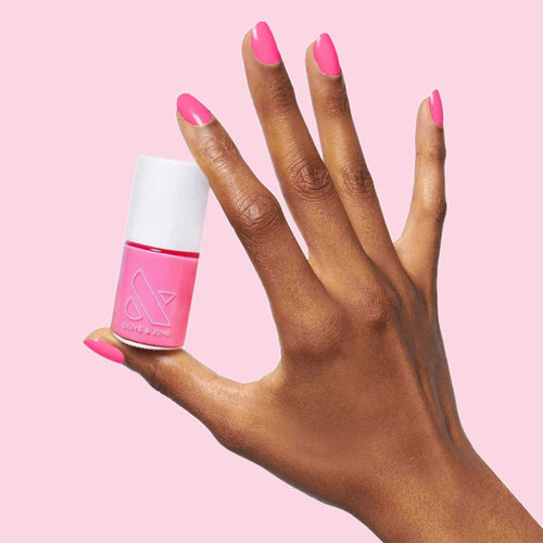 Hand holding Grateful & Kind pure pink gel polish bottle with matching manicure for an at-home mani look