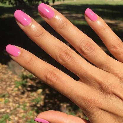 Hand with nails polished in Grateful & Kind pure pink gel polish for a vibrant and long-lasting mani by Olive and June