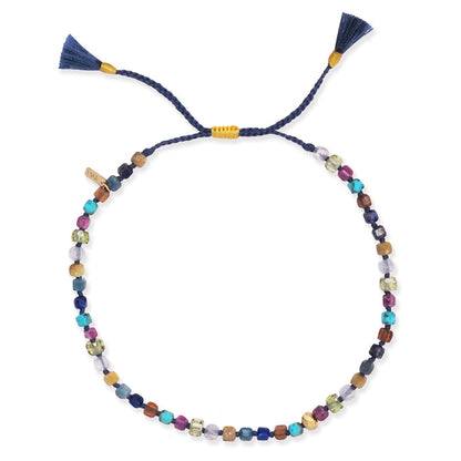 Multistone beaded bracelet on navy cord with small knots and gold accents, tassel ends