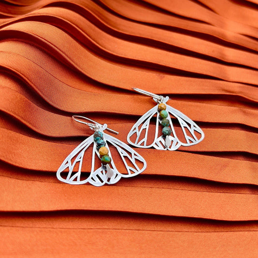 Handmade Peppered Moth earrings by Fluff Hardware featuring detailed black and white wing patterns on silver hooks.