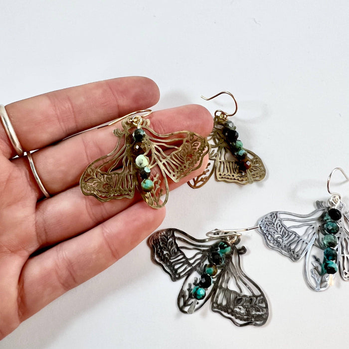 Handmade Peppered Moth earrings by Fluff Hardware, featuring detailed black and white moth design on silver hooks.
