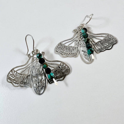 Handmade Peppered Moth earrings by Fluff Hardware featuring detailed black and white moth designs on silver hooks.