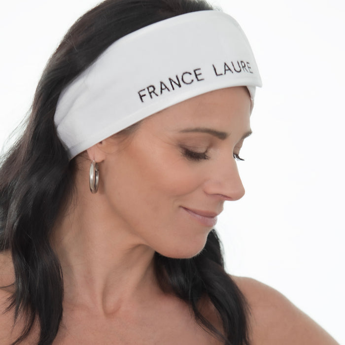 Woman wearing white France Laure headband for skincare routines, featuring elegant branding and soft fabric texture
