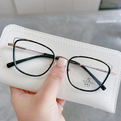 A hand holds EyeCandys Kaylee Cat Eye eyeglasses, featuring black rims with gold accents, resting on a white case; a UV protection label is seen on one lens.