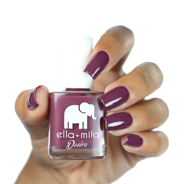 La Vie en Rose purple berry nail polish on a medium skin tone, hand holding the bottle