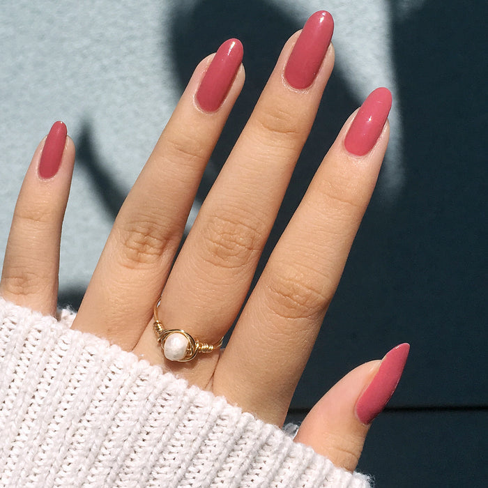 Hand with long nails painted in LD rosy pinky rosewood polish for an elegant at-home manicure look