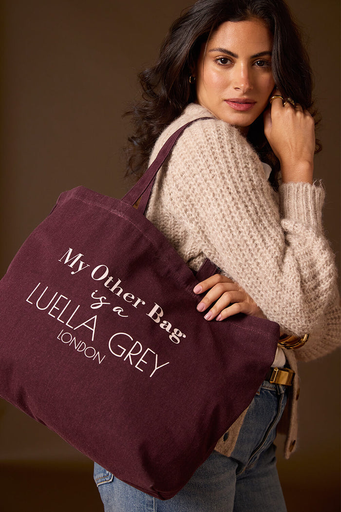 Female model wearing Luella Cherry Canvas Shopper with printed white writing details over her shoulder with two shoulder straps