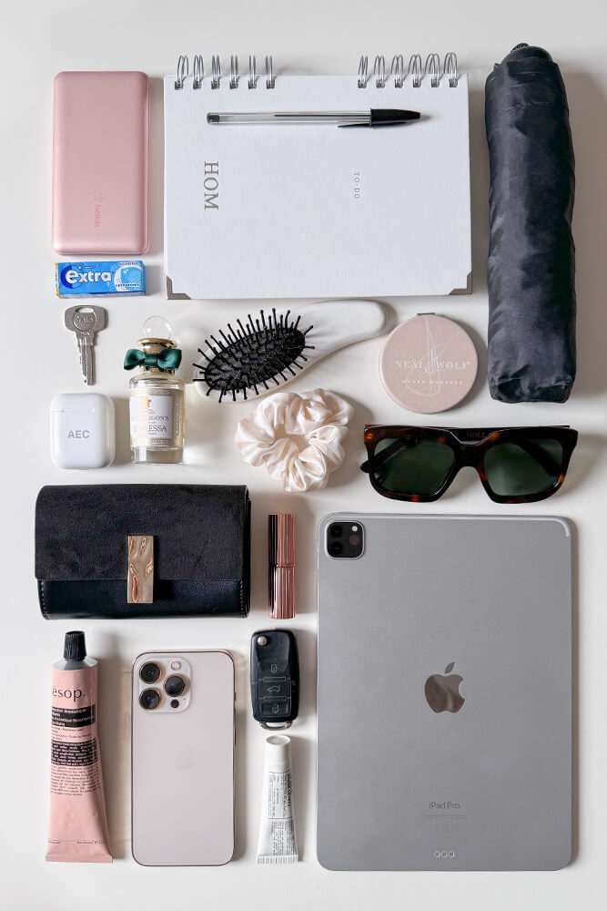 Collection of personal items including a purse, tablet, beauty products, and accessories to show what would fit in the Luella Cherry Canvas Shopper