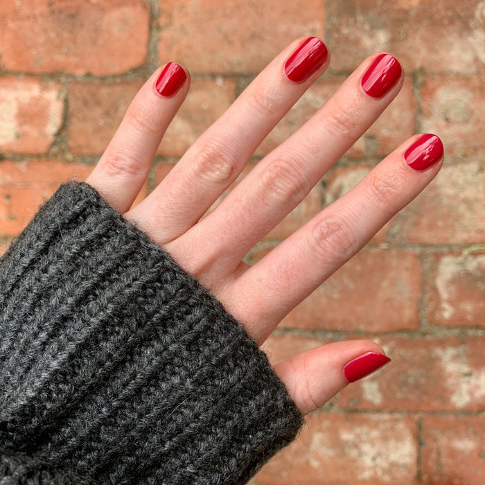 Hand with nails painted in vibrant red using Nailfie Time polish for a smooth, long-lasting manicure look