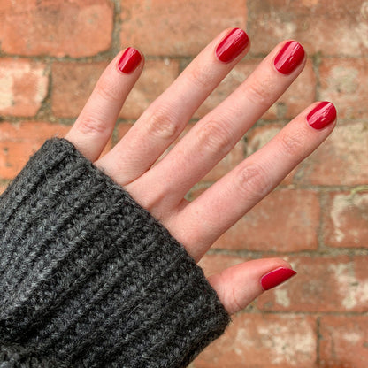 Hand with nails painted in vibrant red using Nailfie Time polish for a smooth, long-lasting manicure look