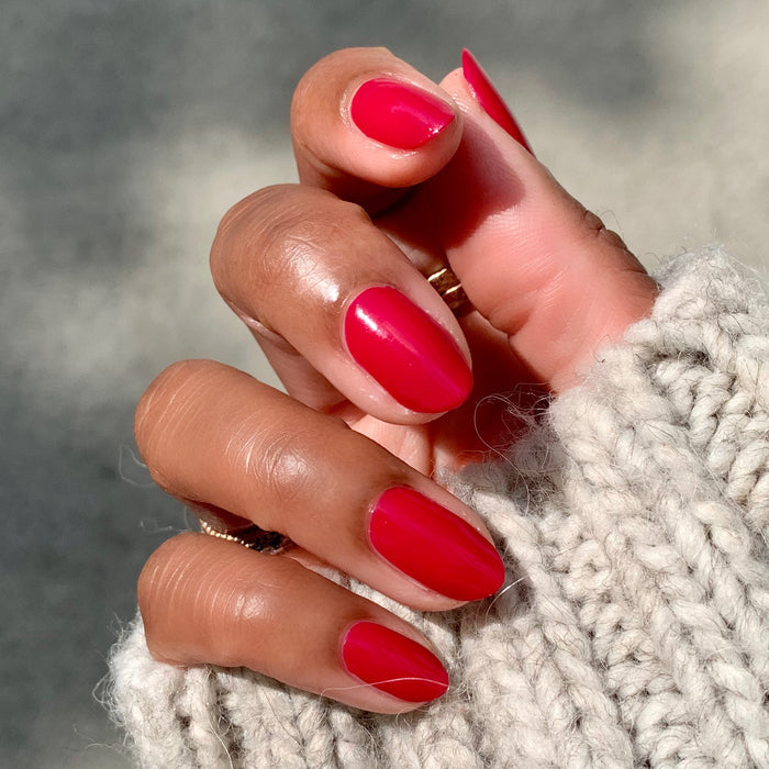 Hand with nails polished in vibrant jewel-toned ruby red using Nailfie Time for a sleek and lasting manicure