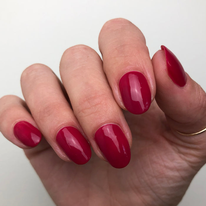 Hand with nails painted in rich ruby red using Nailfie Time polish for a smooth, glossy manicure finish