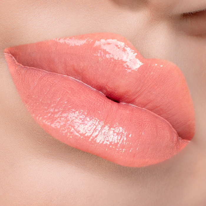 No More Games peach coral lip gloss on lips, light skin tone close-up