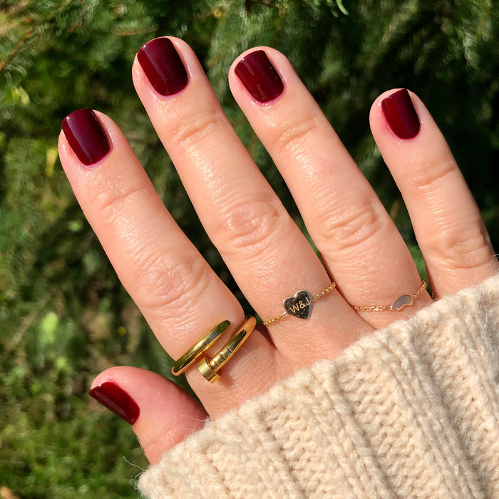 Hand with nails painted in deep rich red using Obsessed polish for a smooth, long-lasting manicure finish
