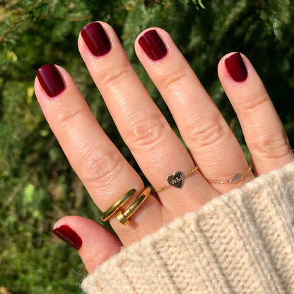 Hand with nails painted in deep rich red using Obsessed polish for a smooth, long-lasting manicure finish