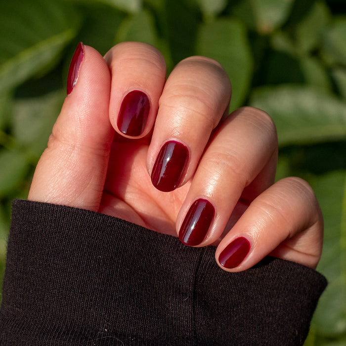 Hand showing manicure with smooth, dark ruby red Obsessed polish for a rich and long-lasting finish
