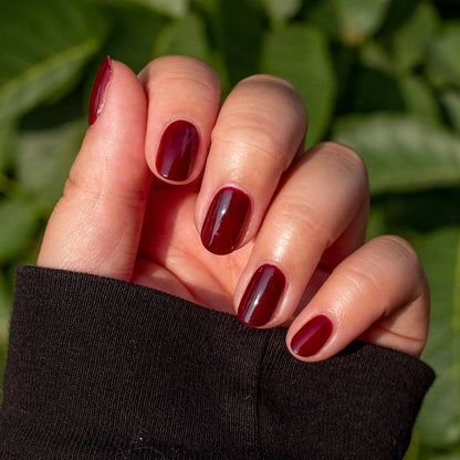 Hand showing manicure with smooth, dark ruby red Obsessed polish for a rich and long-lasting finish