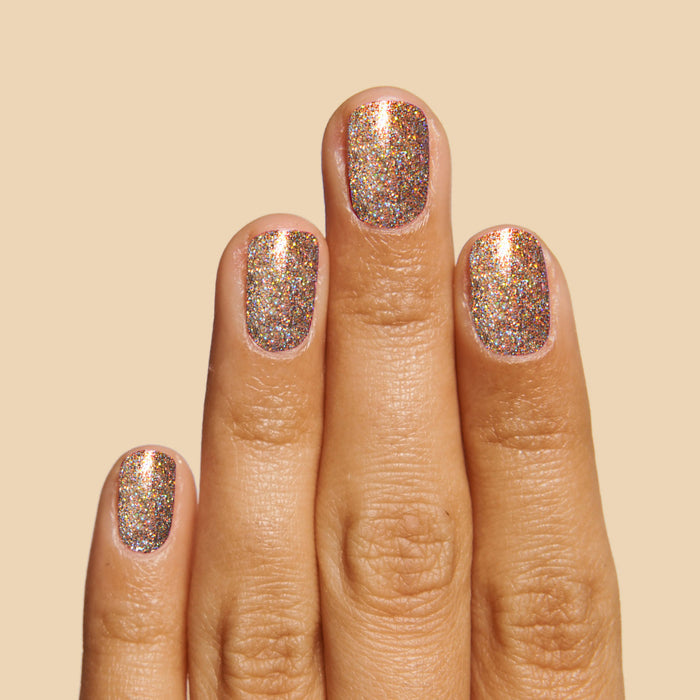 Hand displaying nails painted with OBVI gold glitter polish for a dazzling at-home long-lasting manicure