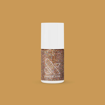 Olive and June OBVI gold glitter polish bottle on tan background for a sparkling, long-lasting mani or at-home manicure