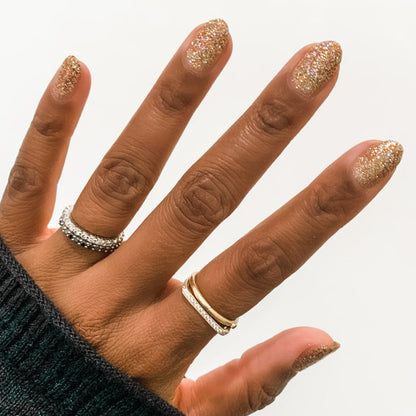 Hand featuring nails coated in Olive and June OBVI shimmering gold polish for an eye-catching at-home manicure