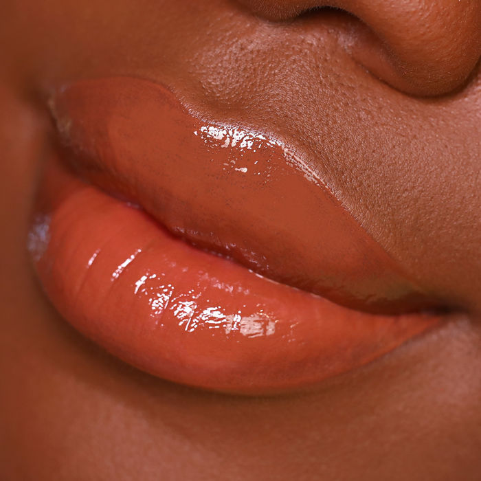 Oh Deer caramel brown lip gloss on lips, deep skin tone close-up