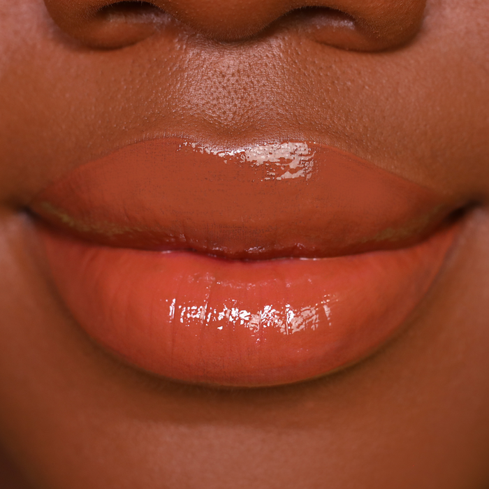 Oh Deer caramel brown lip gloss on lips, medium-deep skin tone